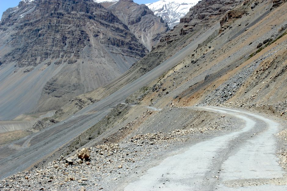 Dramatic winding road through rocky mountain landscape under clear blue sky.