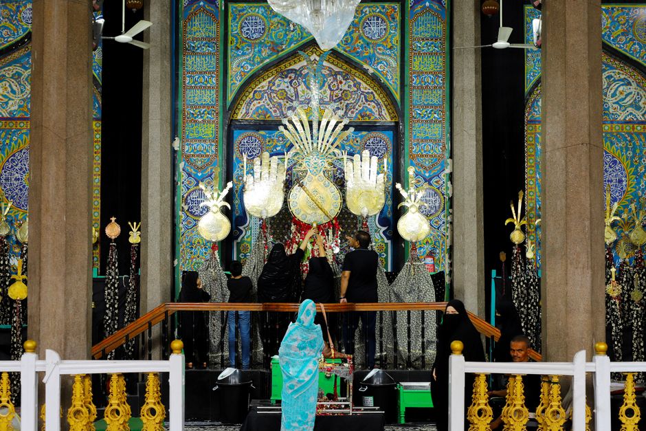 A vibrant and colorful religious ceremony with adorned decorations and people in traditional attire indoors.