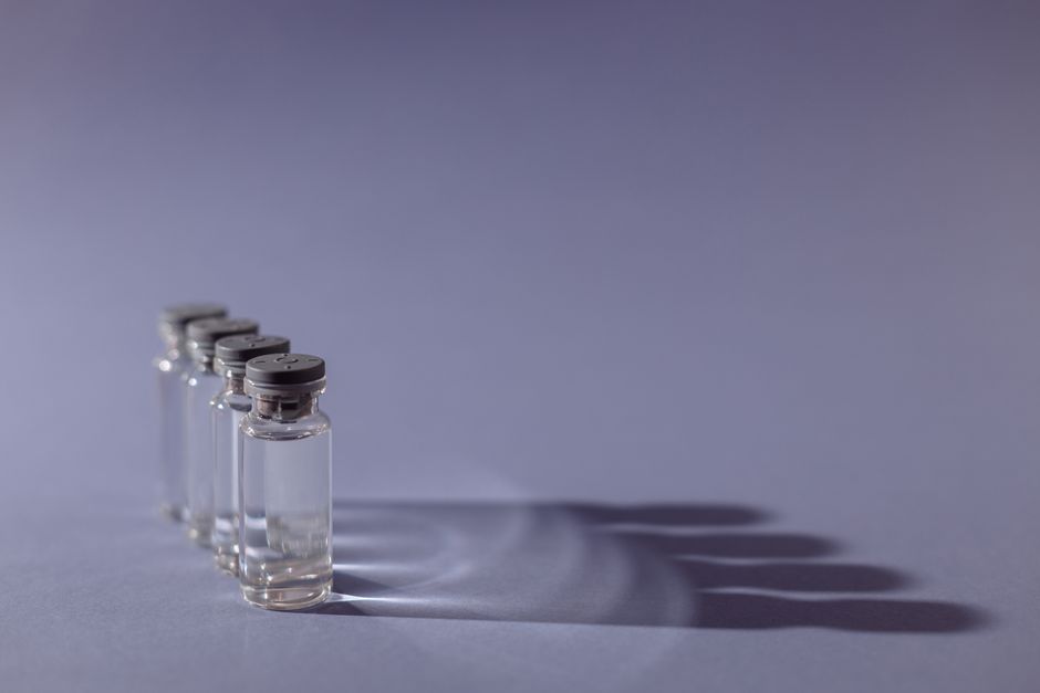 Close-up of lined up vaccine vials casting shadows, symbolizing medical advancements and health.