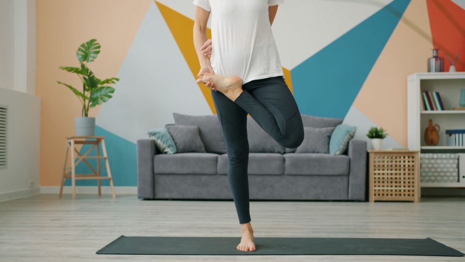 Adult practicing yoga pose in a stylish modern living room with geometric wall design.