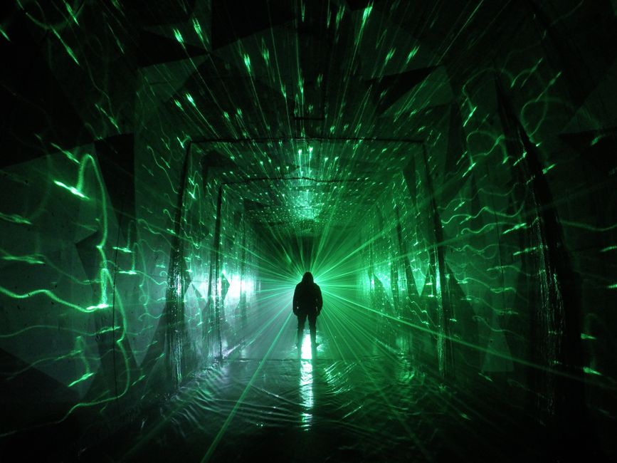 A striking silhouette in a vibrant green laser light tunnel, creating an abstract and immersive experience.