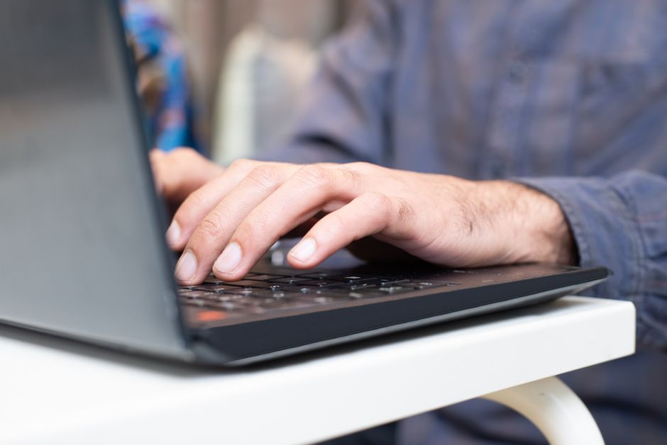 Close-up of hands typing on a laptop keyboard, focused and professional setting.