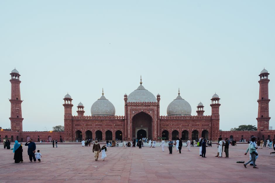 View of the iconic Badshahi Mosque in Lahore with visitors at twilight, showcasing its architectural beauty.
