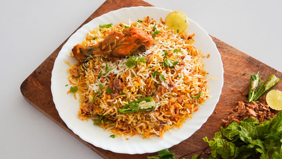 Mouth-watering chicken biryani served on a white plate with herbs and spices.
