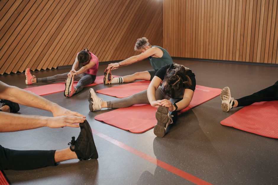 People stretching on exercise mats in an indoor gym during a workout session.
