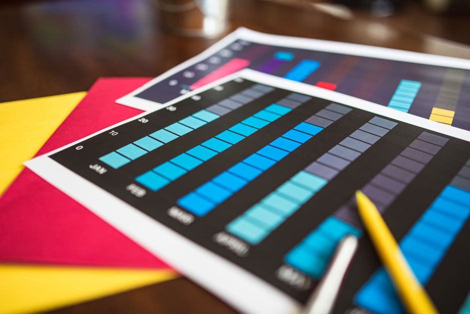 Close-up of colorful financial charts and a pencil on a wooden desk.