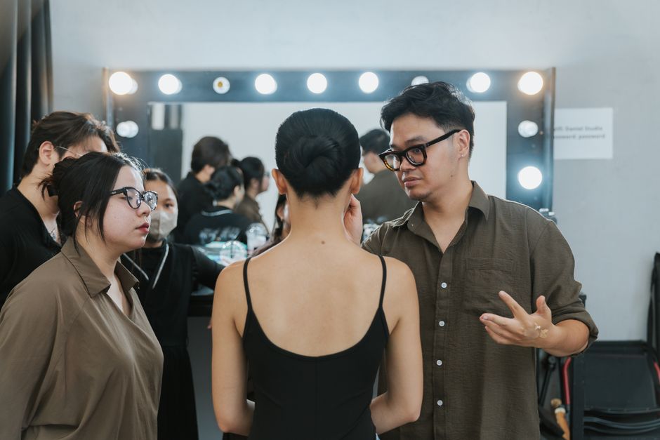 A group of young adults preparing backstage in a fashion studio.