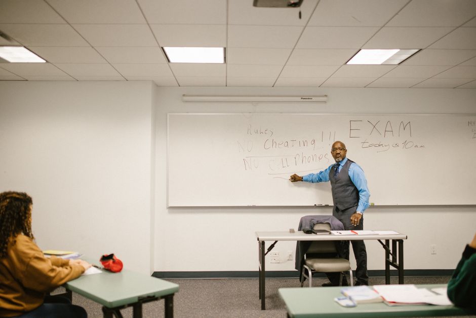 A professor explains exam rules in a college classroom, emphasizing no cheating or phones.
