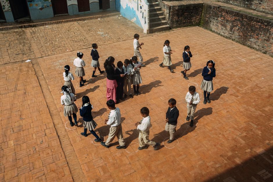 Aerial view of children playing a game on the school courtyard during daytime.