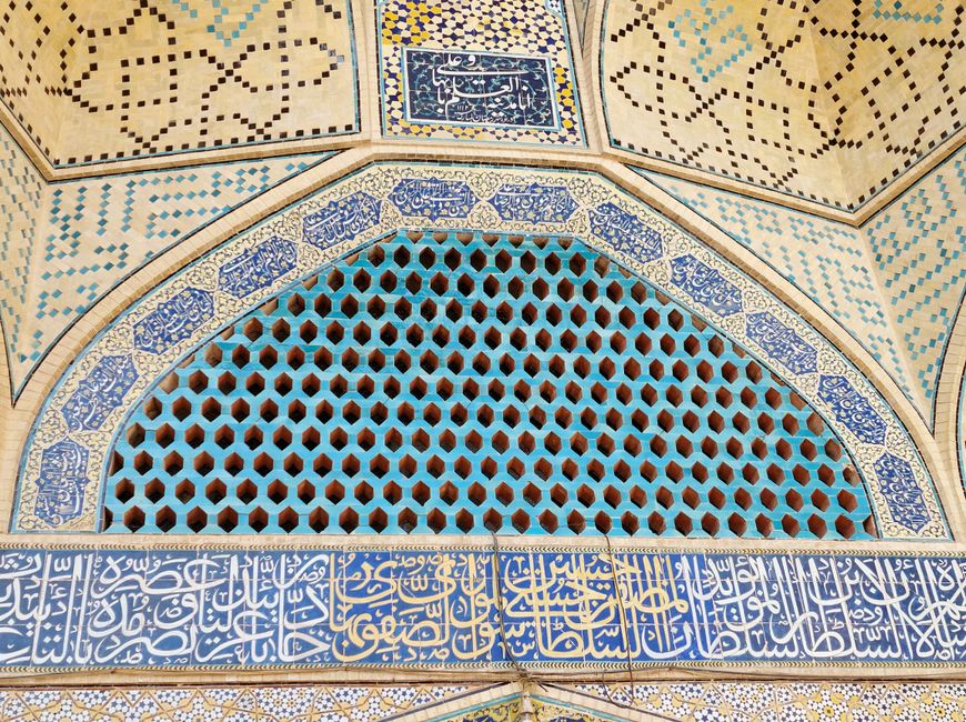 Close-up view of an ornate Islamic tile mosaic featuring Arabic calligraphy and geometric patterns.