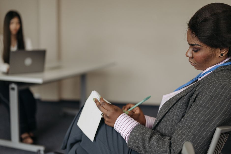 Professional businesswoman taking notes during a meeting in a conference room.