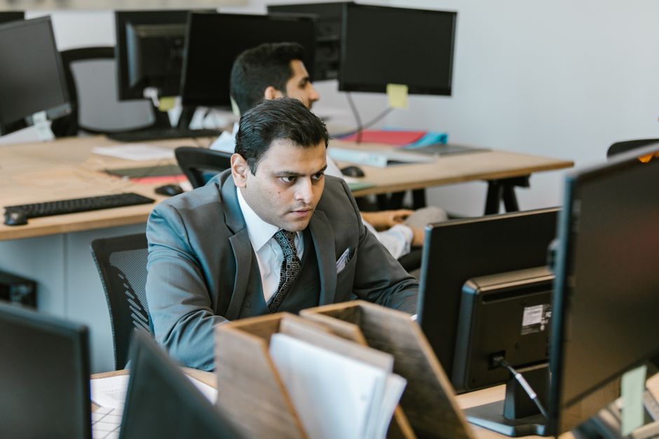 A dedicated businessman in a suit concentrating on work at a modern office desk.
