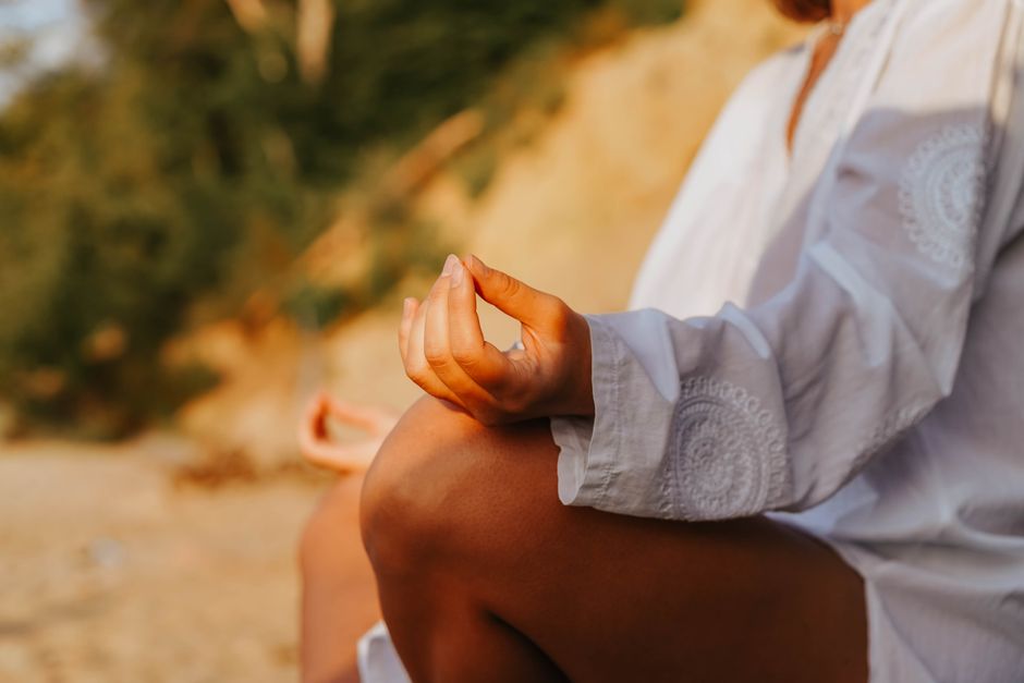 A close-up of a person meditating outdoors, capturing mindfulness at sunset on a beach.