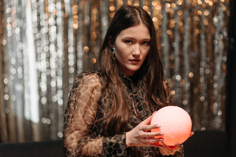 A woman in a leopard print blouse holding a glowing orb, symbolizing mysticism and fortune-telling.