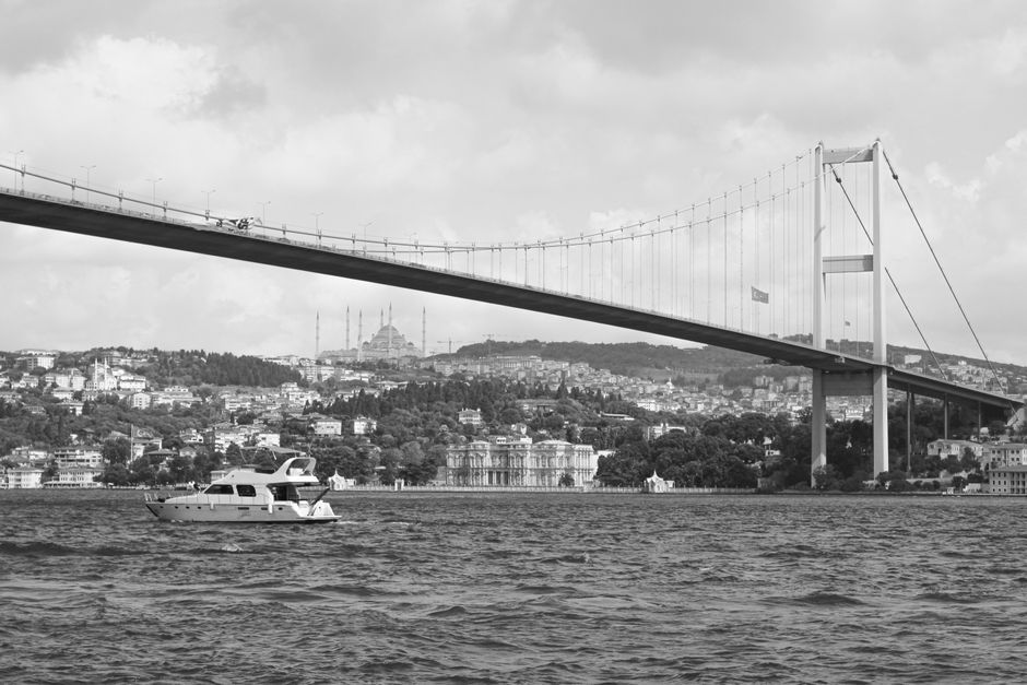 A black and white view of the Bosphorus Bridge and the bustling waters of Istanbul, Turkey.