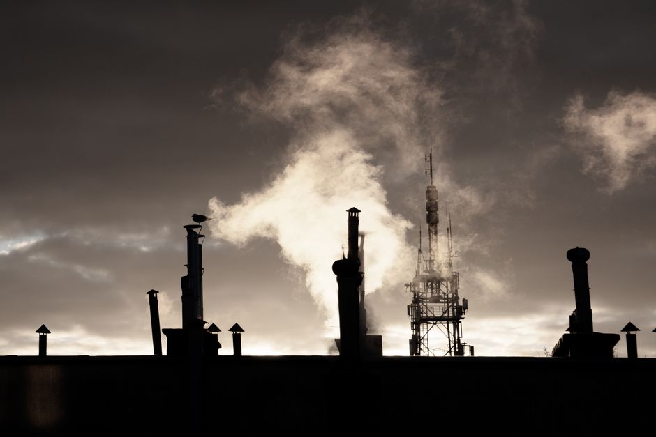 Silhouette of smokestacks emitting smoke against a moody sky, representing industrial emissions.