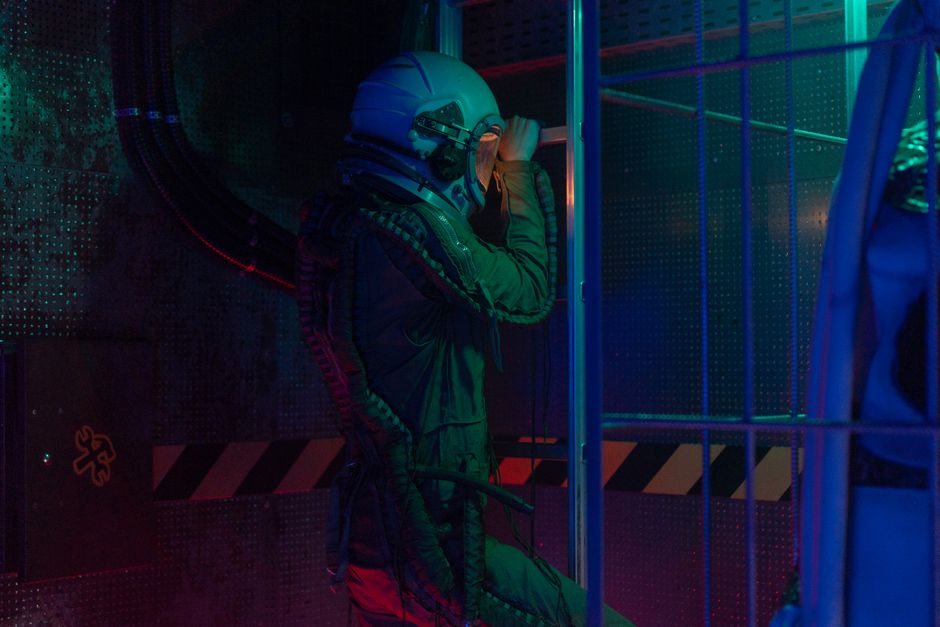 Astronaut in a futuristic setting wearing a space suit, exploring a lit indoor environment.