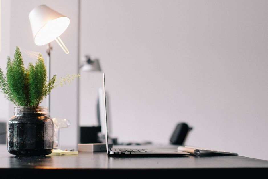 Stylish modern office desk with laptop, lamp, and indoor plant for productive work environment.