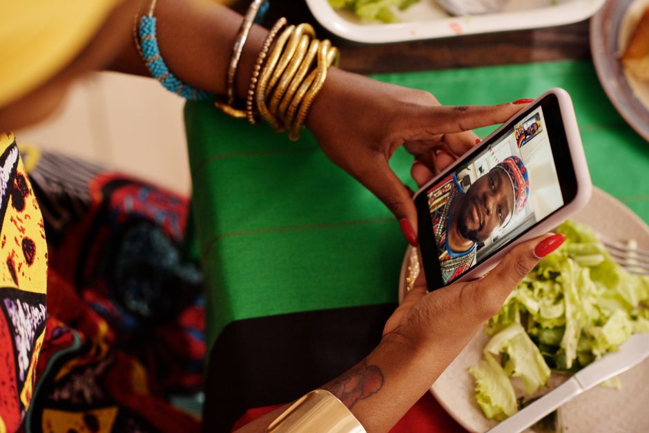 Woman using smartphone for a video call with a festive table setting. Celebrating cultural traditions digitally.
