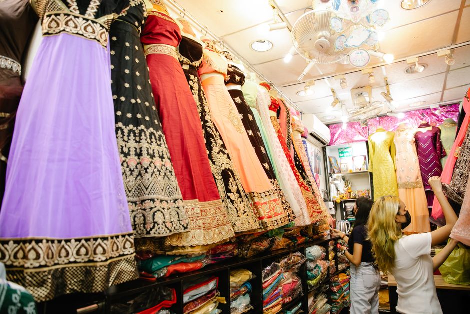 Women browsing vibrant traditional dresses in a lively boutique shop interior.
