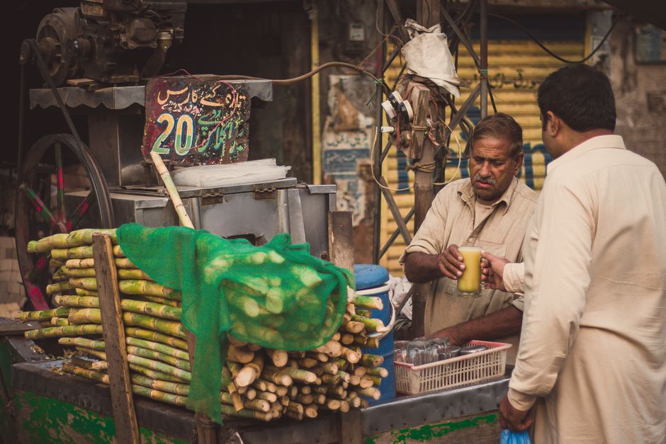 A vendor serves fresh sugarcane juice to a customer at a street stall in Lahore, Pakistan.