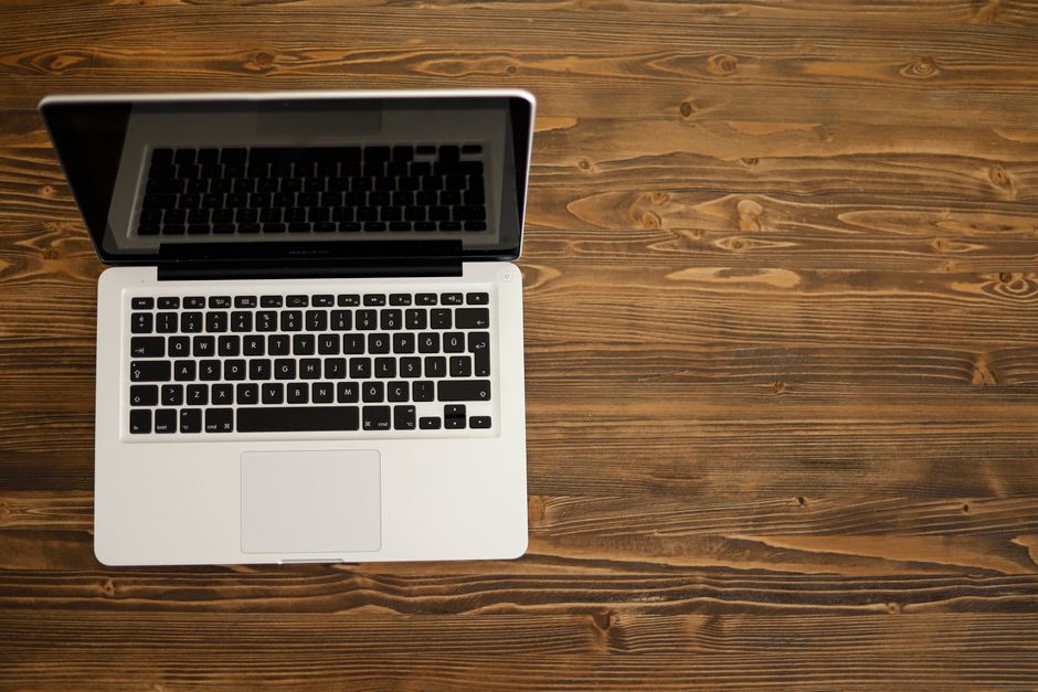 Aerial view of an open laptop on a rustic wooden desk, ideal for technology themes.