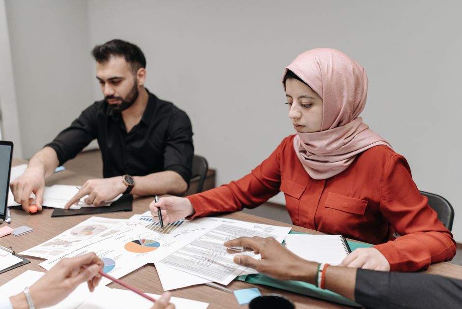 A multicultural office group analyzing documents and charts during a collaborative meeting.