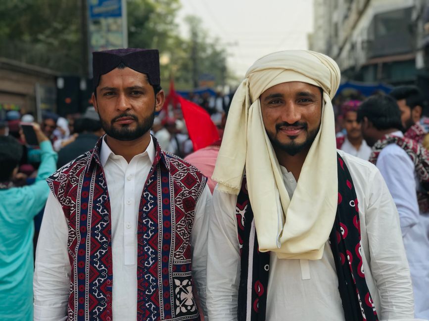 Two men in traditional attire participating in a vibrant cultural street parade.
