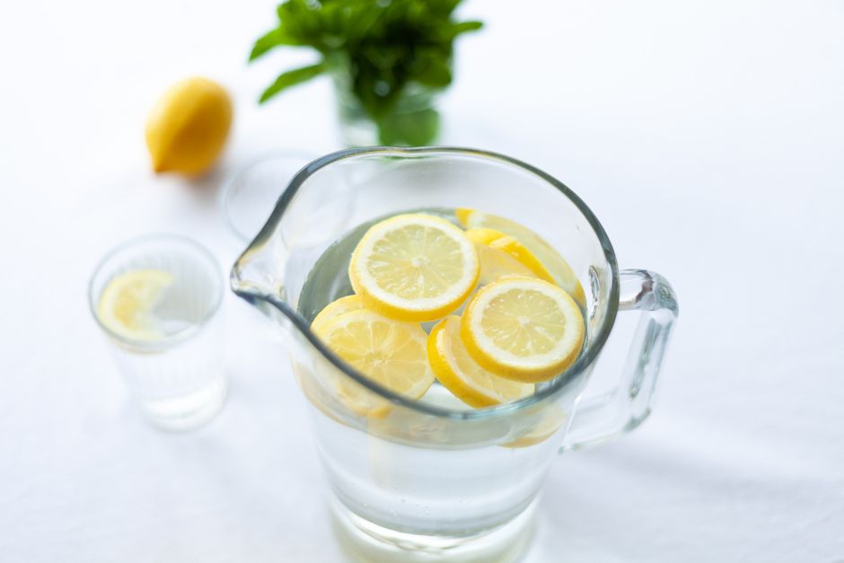 Hydration Top-down view of lemon slices in a glass pitcher filled with water, offering a refreshing drink option.