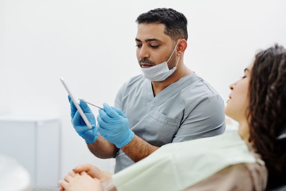 A healthcare professional uses a tablet to consult with a patient in a clinical setting.