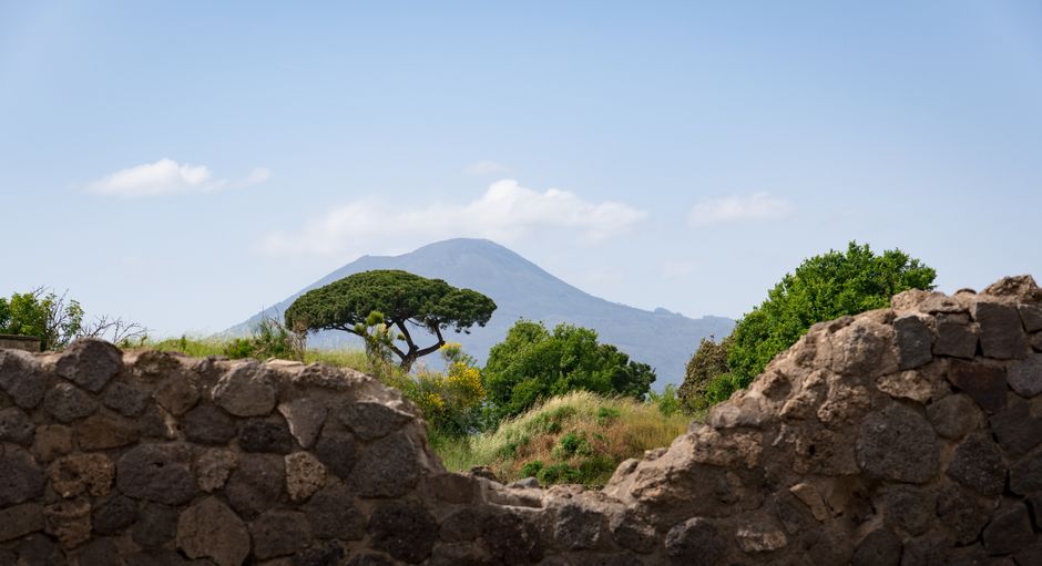 A scenic view of Mount Vesuvius framed by ancient stone ruins in Pompeii, Italy.