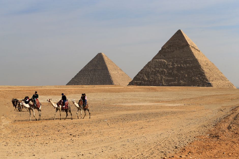 Camel riders journey near the pyramids of Giza, Egypt, capturing an iconic desert scene.