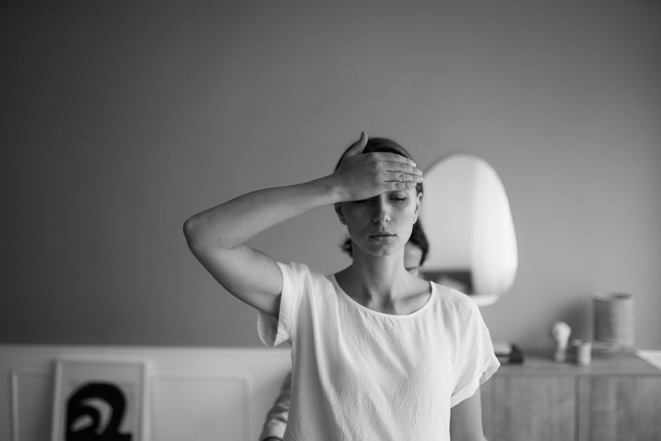 Black and white image of a woman with her hand on forehead, eyes closed and serene.