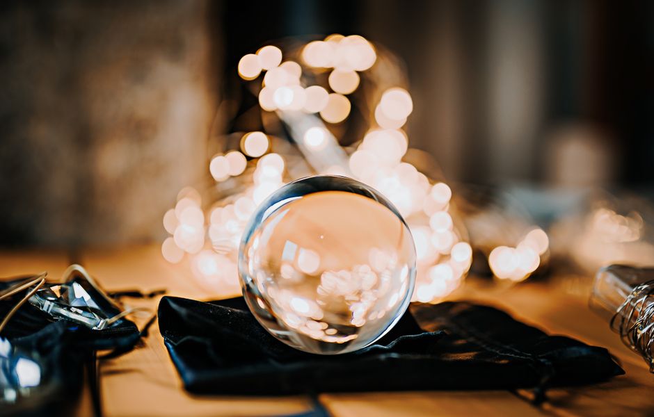 A glass ball on a table with warm bokeh lights in the background.