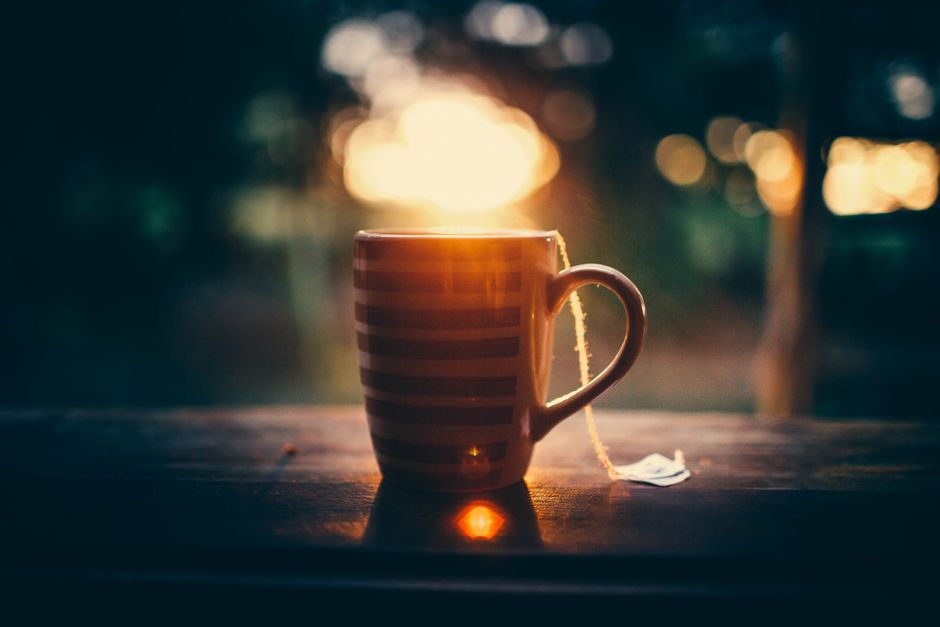 Sunrise over tropical resort with cup of hot tea placed on wooden table on terrace