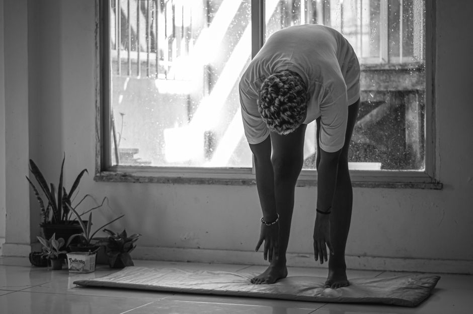 A person in Brazil stretching indoors during a rainy day in black and white.
