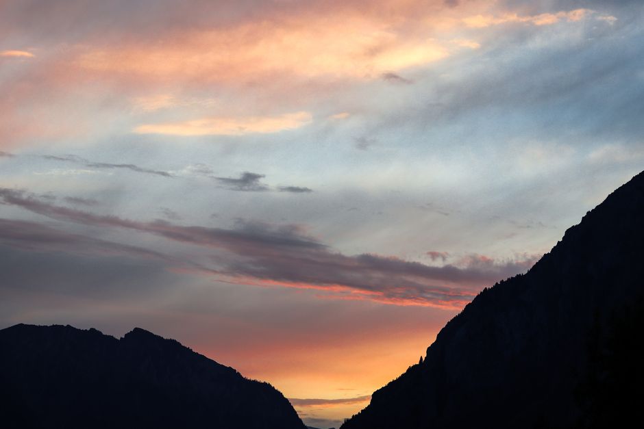 Stunning view of a colorful sunset over silhouetted mountain peaks, creating a dramatic sky.