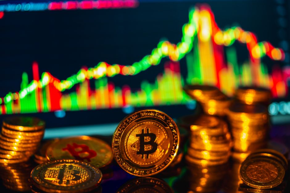 Golden bitcoins stacked in foreground with a financial graph in the background, symbolizing digital investments.