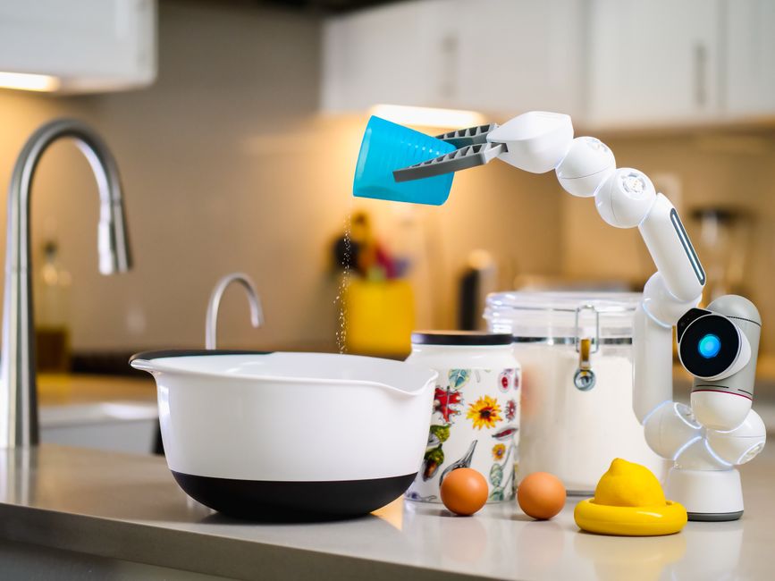 A robotic arm carefully pouring ingredients into a mixing bowl in a modern kitchen setting.