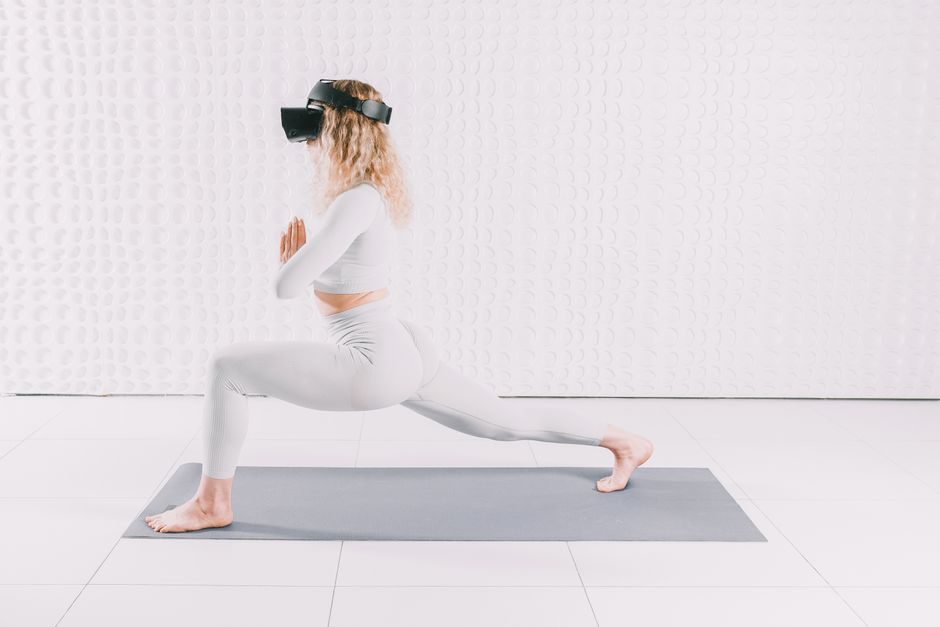 Smart Contact Lenses Adult woman in yoga pose wearing VR headset, exploring virtual reality indoors on a mat.