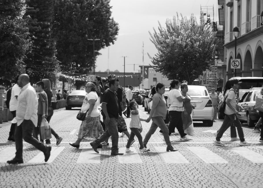 Pedestrians crossing a street in Xalapa, Mexico, showcasing urban life and architecture.