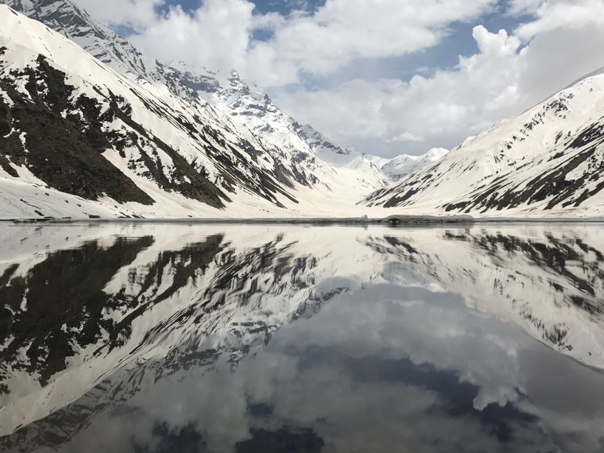 Beautiful snow-capped mountains reflecting on a serene lake with a clear sky above.
