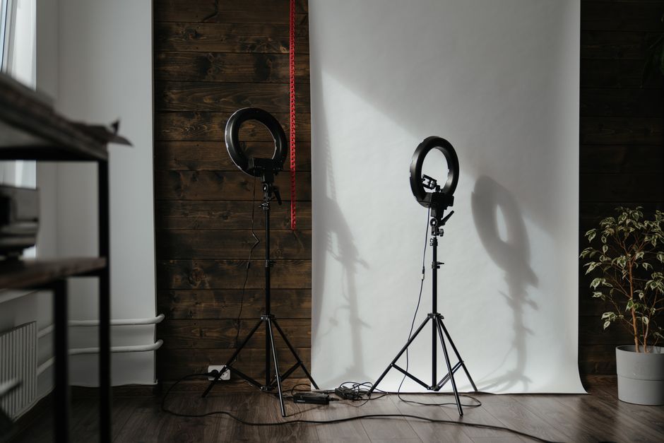 A modern photo studio setup with ring lights and wooden backdrop, ready for a photoshoot.