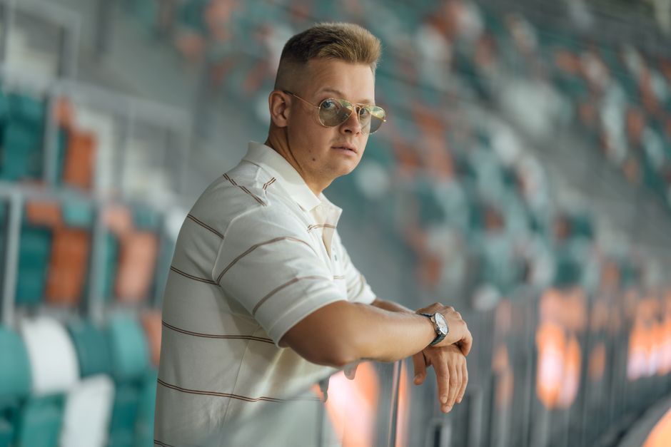 Young man in sunglasses leaning on stadium seats. Casual style vibe.