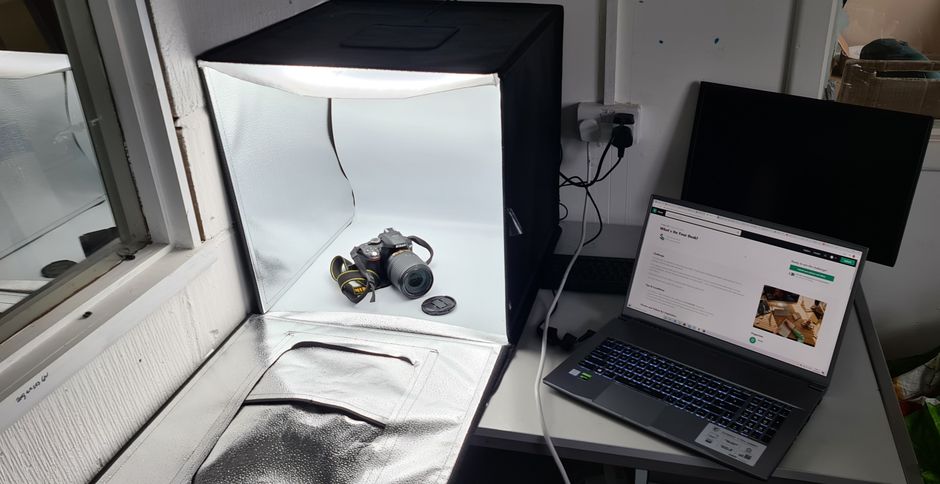 Photography workspace featuring a light box, DSLR camera, and laptop.