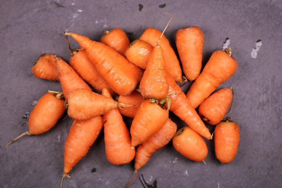 Top view of fresh organic carrots on a dark surface, highlighting their vibrant orange color.