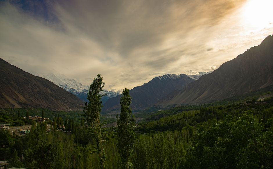 Breathtaking view of Hunza Valley at sunset with lush greenery and majestic mountains.