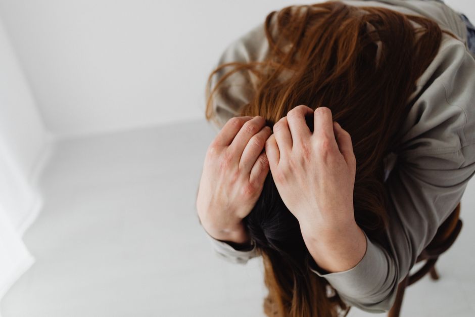 Overhead view of a woman with long hair grasping her head, depicting stress and emotion.